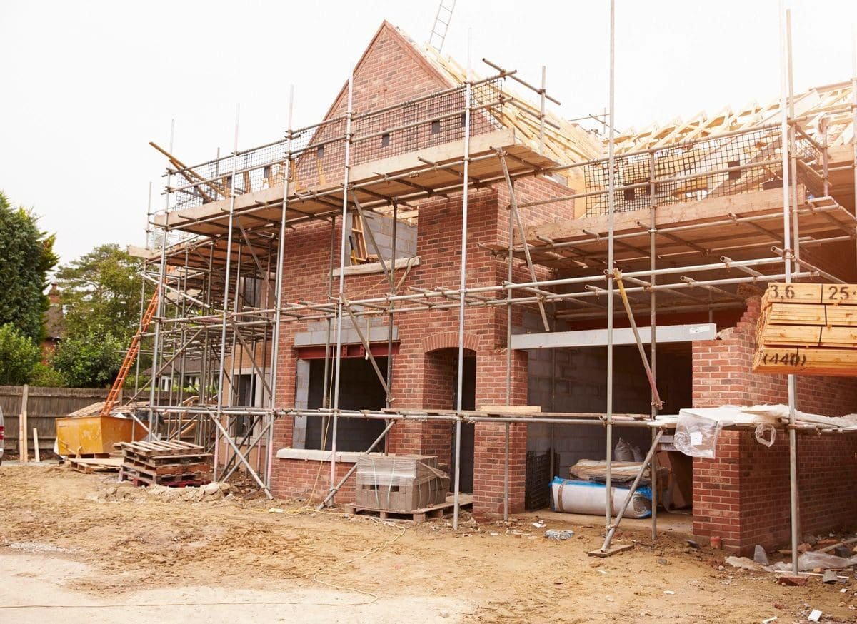 Brick house under construction with scaffolding.