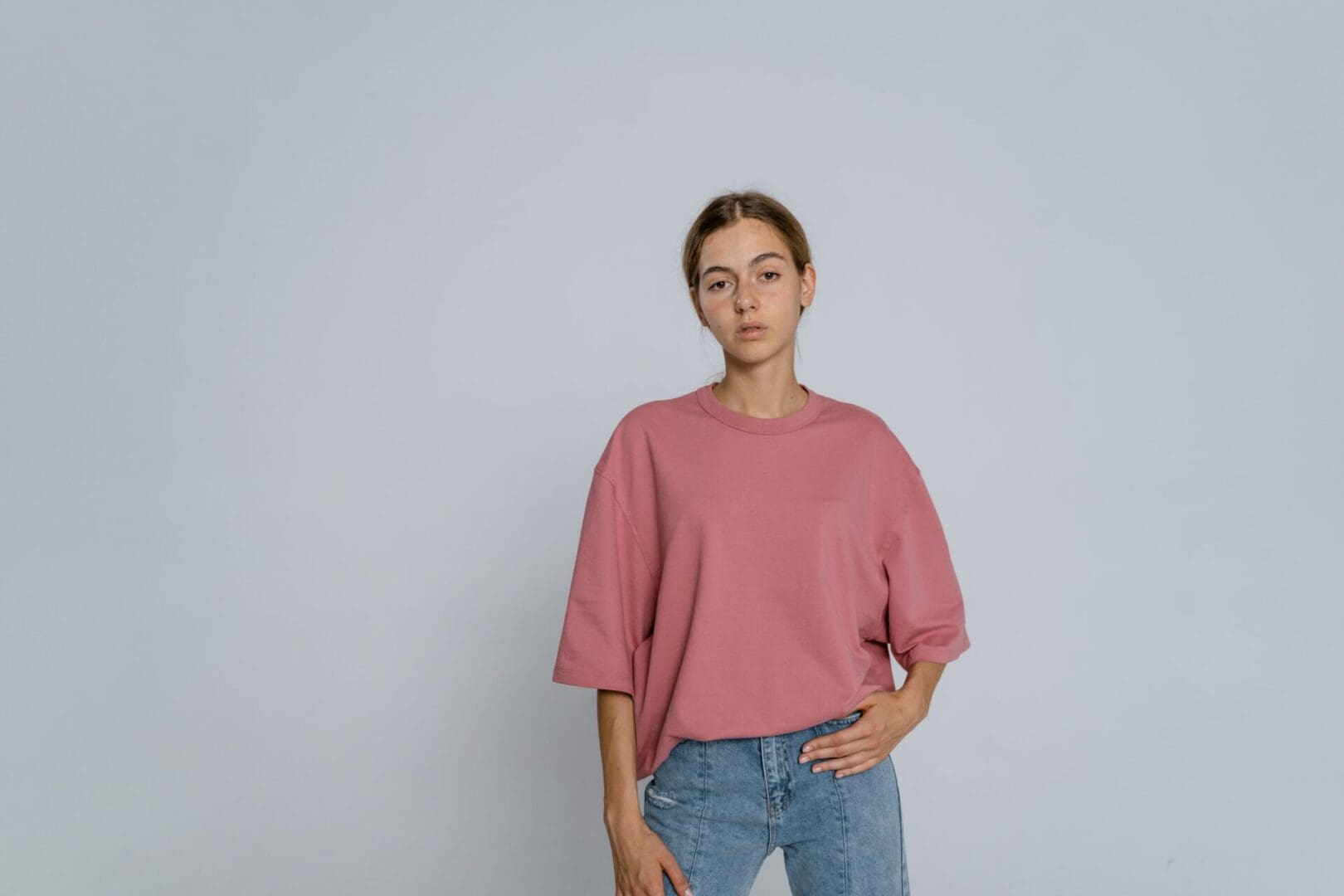 Woman wearing a pink shirt and jeans.