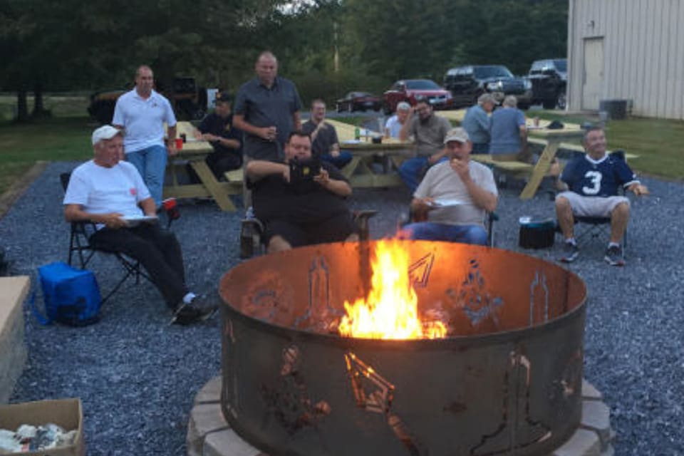 Group of men gathered around a fire pit.